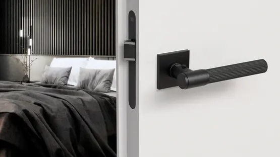 eine weiße Tür mit schwarzem Griff öffnet sich ins Schlafzimmer 